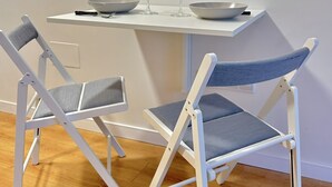 Een eethoek met een witte tafel en twee opklapbare stoelen.