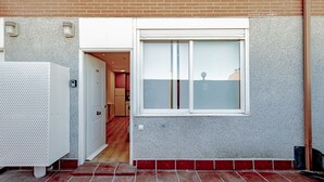 Un vestíbulo residencial con piso de baldosas, una puerta blanca y un ventanal con vidrio esmerilado.