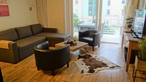 Moderni olohuone, jossa on sohva, kaksi nojatuolia, sohvapöytä ja lehmännahkamatto.
