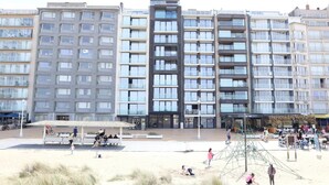 A modern building with multiple floors and balconies, a central open plaza with benches, and a playground area. - Studio in Nieuwpoort near the Beach (Nieuwpoort)