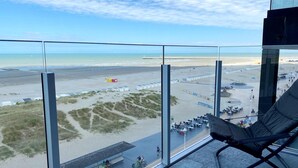 A view from a high-rise hotel room overlooking a beach with a sandy shore, a pier, and a circular plaza with seating. - Studio in Nieuwpoort near the Beach (Nieuwpoort)