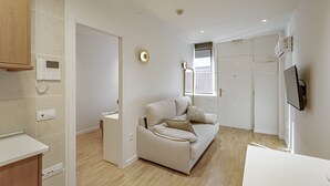 A modern living room with a beige sofa, a small table, and a TV mounted on the wall. - New Apartment Madrid Feria 103 (Madrid)