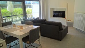 Een moderne woonkamer met een bank, een eettafel en een televisie.