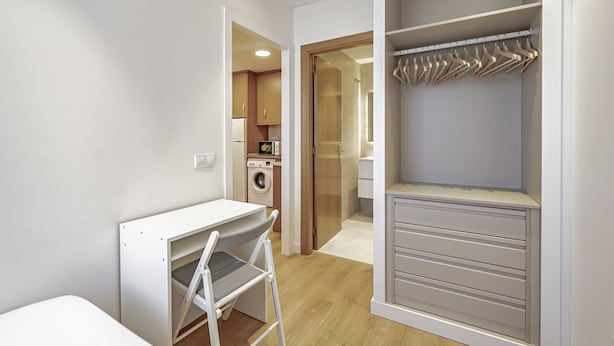 Un dormitorio moderno con escritorio integrado, vestidor y baño independiente.