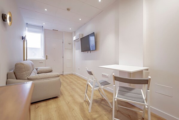 A modern living room with a sofa, a dining table, and chairs.