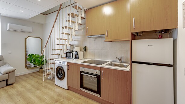 A modern kitchen with wooden cabinets, a built-in oven, a washing machine, and a refrigerator.