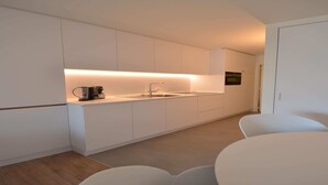 A modern kitchen with white cabinetry, a built-in oven, and a countertop with a coffee maker. - Coastal Retreat with Terrace (Oostduinkerke)
