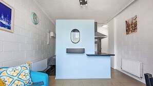A modern living room with a blue sofa, a small table, and a light blue partition. - In the Heart of the City – Quaint Studio in the Prime Location! (Melbourne)