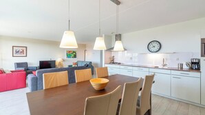 Een moderne keuken met witte kasten, een houten eettafel en hanglampen.