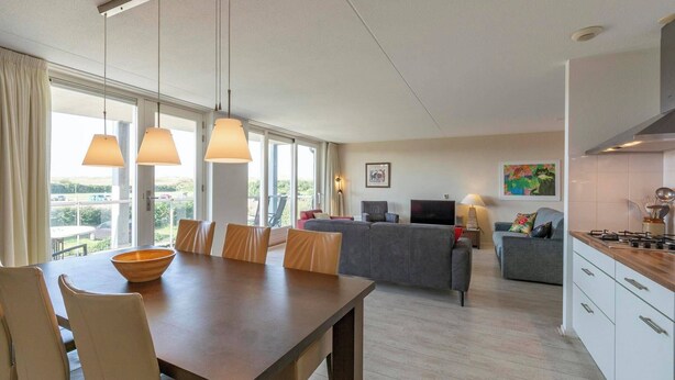 Een moderne keuken met een eethoek, grote ramen en uitzicht op de omgeving.