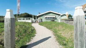 Een pad dat naar een groen gebouw leidt, met een bord waarop 'KEET' staat.