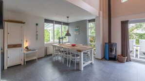 A spacious kitchen with a dining table, chairs, a stove, and large windows.
