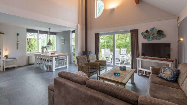 A spacious living area with a large TV, comfortable seating, a dining area, and a view of the outdoors.