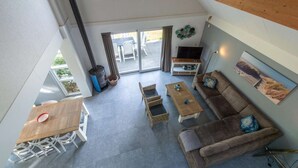 A spacious living area with a sofa, coffee table, and a TV. There is a sliding glass door leading to an outdoor patio.