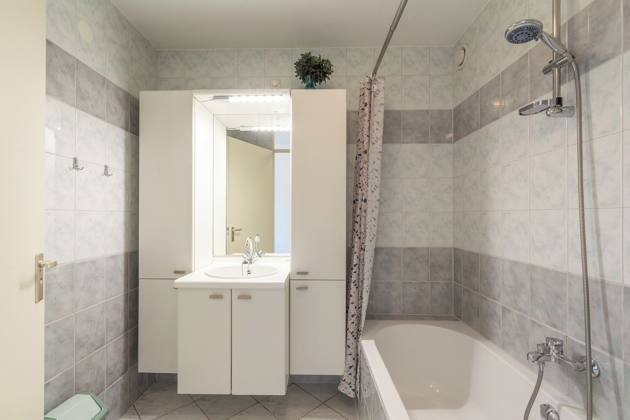 A bathroom with a bathtub, a shower, a sink, and a mirror.