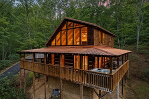 Eine Hütte mit großer Terrasse, Whirlpool und Blick auf den umliegenden Wald.