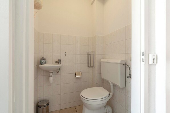 Un baño pequeño y limpio con inodoro, lavabo y cubo de basura.
