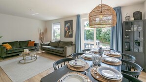 A modern living room with a dining area set for a meal.