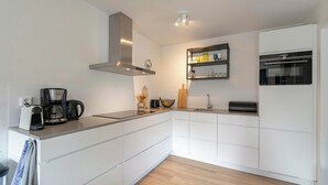 A modern kitchen with white cabinetry, a built-in oven, a coffee maker, and a sink.