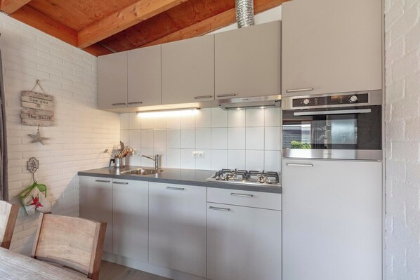 A compact kitchen with white cabinets, a stainless steel gas stove, and a built-in oven.