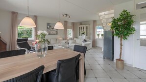 Ein modernes Wohnzimmer mit Essbereich, weißen Möbeln und einer Topfpflanze.