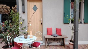 Eine Terrasse im Freien mit einem runden Tisch, roten Kissen und einer hölzernen Bank.