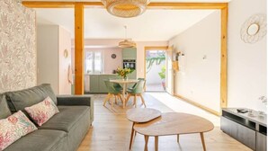 Ein modernes Wohnzimmer mit einer Couch, einem Esstisch und einer Küche im Hintergrund.