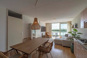 A modern kitchen with a dining area, a sofa, and a view of the outdoors. - Apartment in Groote Keeten near the Beach (Groote Keeten)