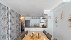A modern dining area with a long table, grey upholstered chairs, and a decorative centerpiece.