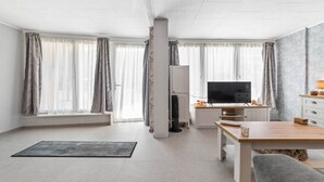 A modern living room with a flat-screen TV, a dining table, and a sofa.