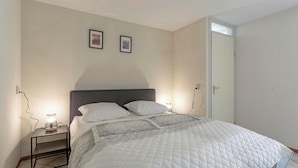 A bedroom with a bed, bedside lamps, and two framed pictures on the wall. - Pet-Friendly Apartment (Callantsoog)