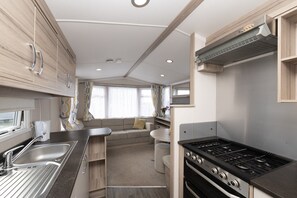 Enjoy a self-contained cooking and dining experience with a compact kitchenette featuring a stainless steel sink, gas stove, and compact oven.