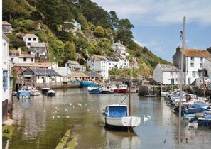 Stunning coastal village with a picturesque harbor and boats, surrounded by lush hills and greenery.