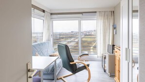 A modern living room with a sofa, a chair, a table, and a TV. - Studio Apartment in Seaside with Panoramic Views (Middelkerke)