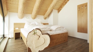 Un dormitorio con una cama de madera, un cabecero con forma de corazón y techo de madera.