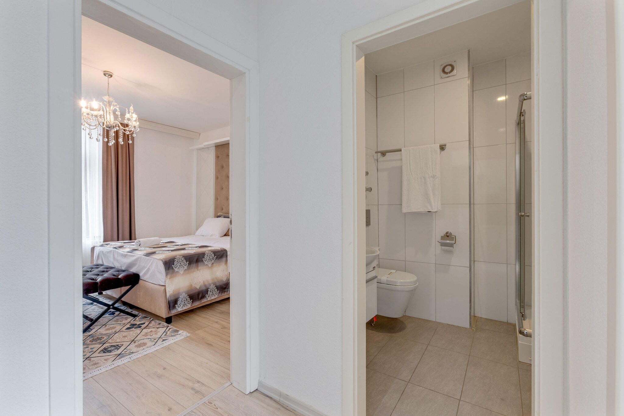 Un dormitorio con cama, una lámpara de araña y un baño con ducha e inodoro.
