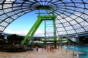 An indoor swimming pool with a glass ceiling and a water slide. - Oberhausen Urban Retreat (Oberhausen)