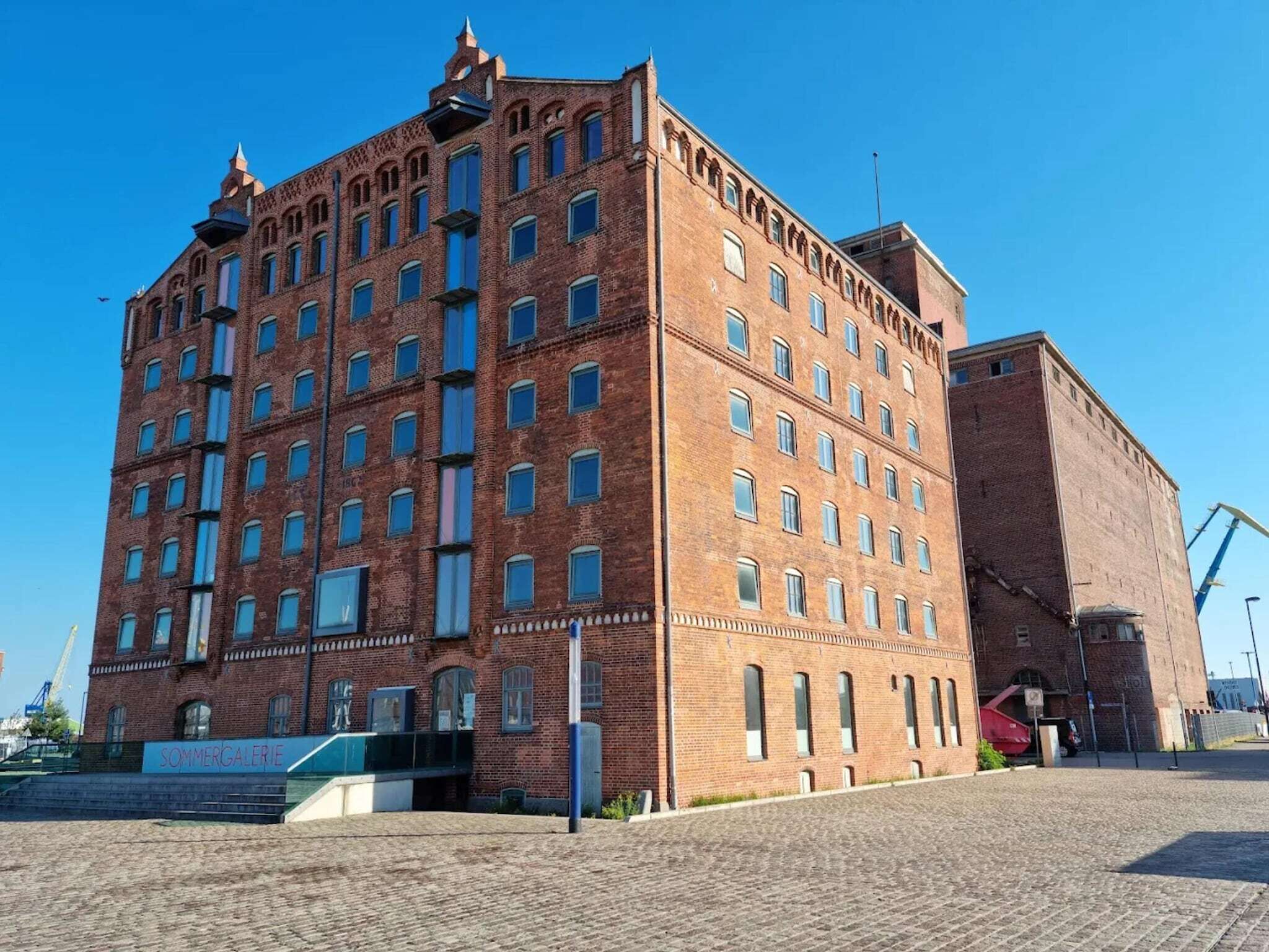 A large brick building with multiple windows and a sign reading "SOMMERGALERIE".