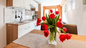 A modern kitchen with white cabinets, a wooden countertop, and a vase of red tulips on the table. - Apartment in Sankt Gallenkirch near Ski Slopes (Vorarlberg)