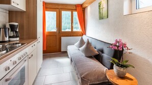 A compact kitchen with a stove, coffee maker, and a window with curtains. - Apartment in Sankt Gallenkirch near Ski Slopes (Vorarlberg)