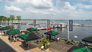 Ein Restaurant am Wasserufer mit Außenbereich und Sonnenschirmen mit Heineken-Logo.