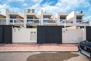 A modern residential building with multiple floors, large black gates, and a parked car. - Villa in Rojales with Pool near Coast (Rojales)
