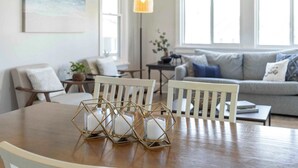 Un coin repas avec une table en bois, des chaises blanches et un chandelier au design géométrique.
