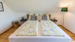 Een tweepersoonsbed met bloemenbeddengoed, twee nachtkastjes met lampen, en een vloerlamp.