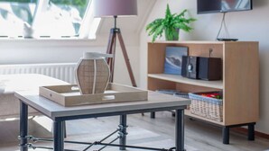 Een moderne woonkamer met een tafel, een lamp, een boekenkast en een televisie.