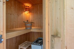 Eine Holzsauna mit Eimer, einer Stufe und einem Mülleimer.
