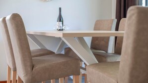 Een eettafel met vier stoelen, een fles wijn en een decoratief wandobject.