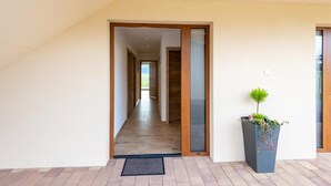 A modern hallway with a wooden door frame and a potted plant.
