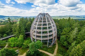 A multi-level observation tower with a spiral staircase, surrounded by dense forest and a view of a town in the distance. - Appartement Elena mit Pool und Sauna (Freyung)