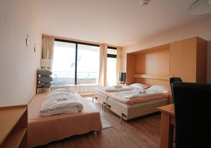 Une chambre d’hôtel avec deux lits, un bureau, une chaise et une vue sur l’extérieur.